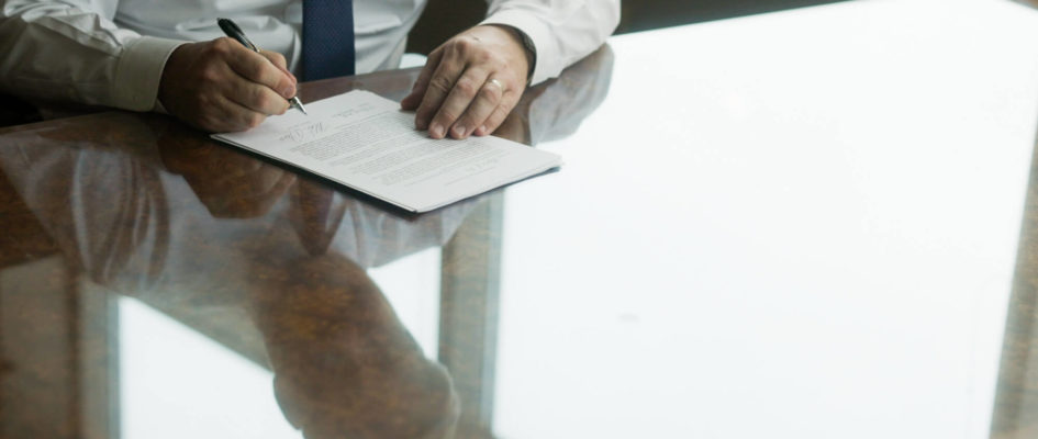 Attorney signing documents on a desk